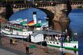 A model of a boat is docked under a bridge.