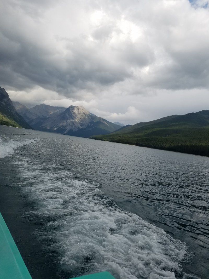A boat is going down a lake with mountains in the background.