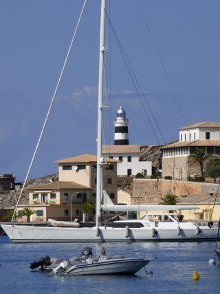 A sailboat in the water with a lighthouse in the background