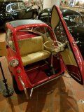 A small red car with the door open is sitting on a tiled floor.