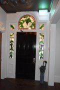 A hallway with a black door and a stained glass window.