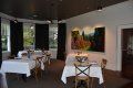 A dining room with tables and chairs and a painting on the wall.