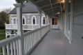 A long hallway leading to a large white house with a porch.