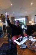 A man is sitting in a chair holding a glass of wine in a living room.