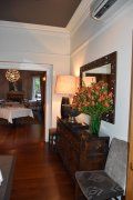 A living room with a dresser , chair , lamp and mirror.