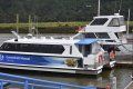 Two boats are docked at a dock on a river.