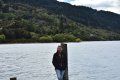 A woman is standing on a dock next to a lake.