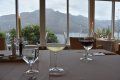 Two glasses of wine are sitting on a table in front of a window.
