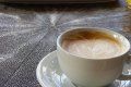A cup of coffee is sitting on a saucer on a table.