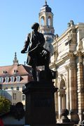 A statue of a man sitting on a horse in front of a building.