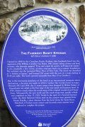 A blue plaque is sitting on a stone wall.