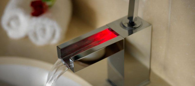 A bathroom sink with a faucet that has a red light on it.