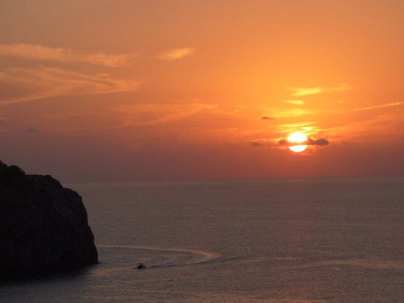 A sunset over the ocean with a boat in the foreground