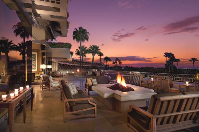 A patio with a fire pit and a sunset in the background