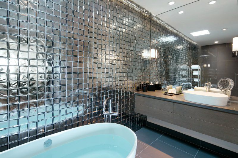 A bathroom with a bathtub , sink and mirror.