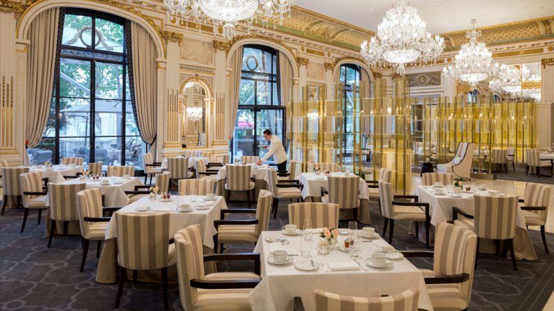 A large dining room filled with tables and chairs and chandeliers.