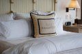 A bed with white sheets and pillows in a hotel room.