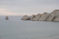 There are a lot of rocks in the water and a boat in the distance.