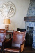 A living room with chairs , a fireplace and a lamp.