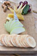 A wooden cutting board topped with sliced fruit and crackers.
