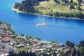 An aerial view of a lake with a parachute flying over it.