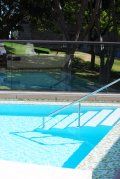A swimming pool with stairs leading to it and trees in the background.