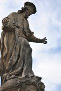 A statue of a man standing on top of a stone pillar.