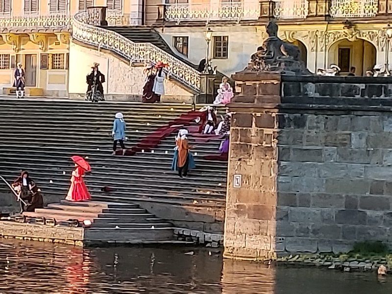 A group of people are standing on a set of stairs next to a body of water.