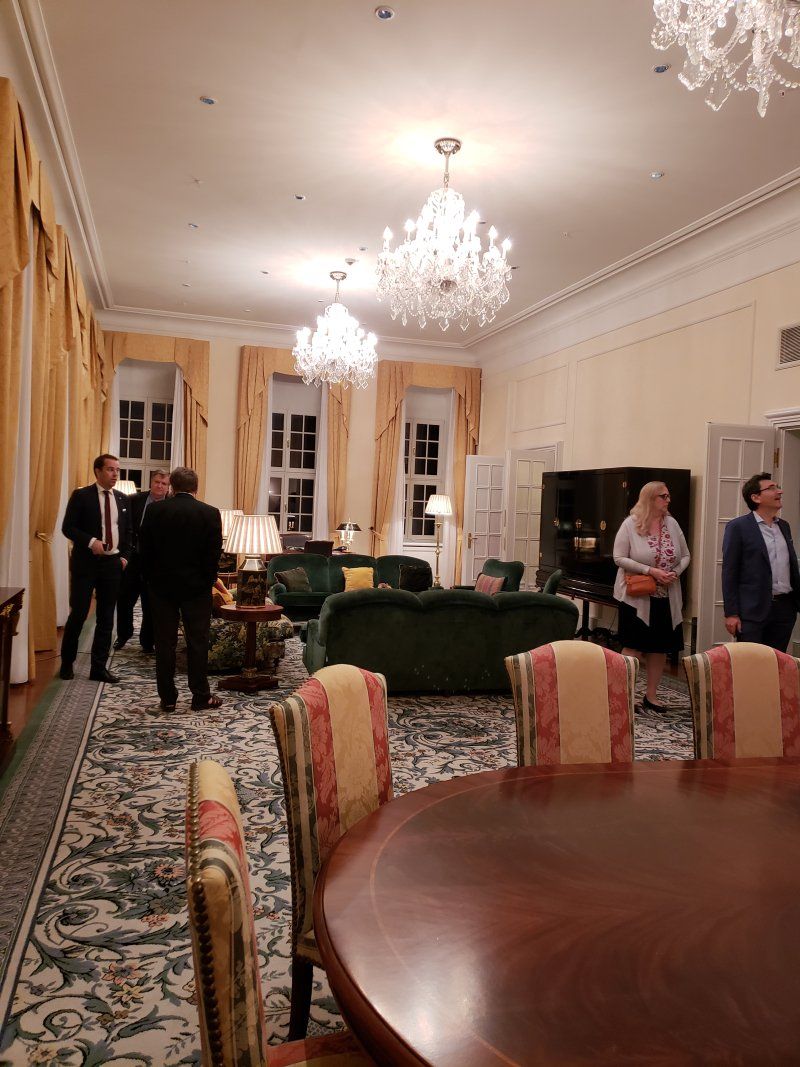 A group of people are standing in a living room with a table and chairs.