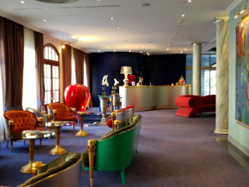 A hotel lobby with a green couch and red chairs