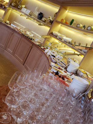 A buffet with lots of food and wine glasses on a table.