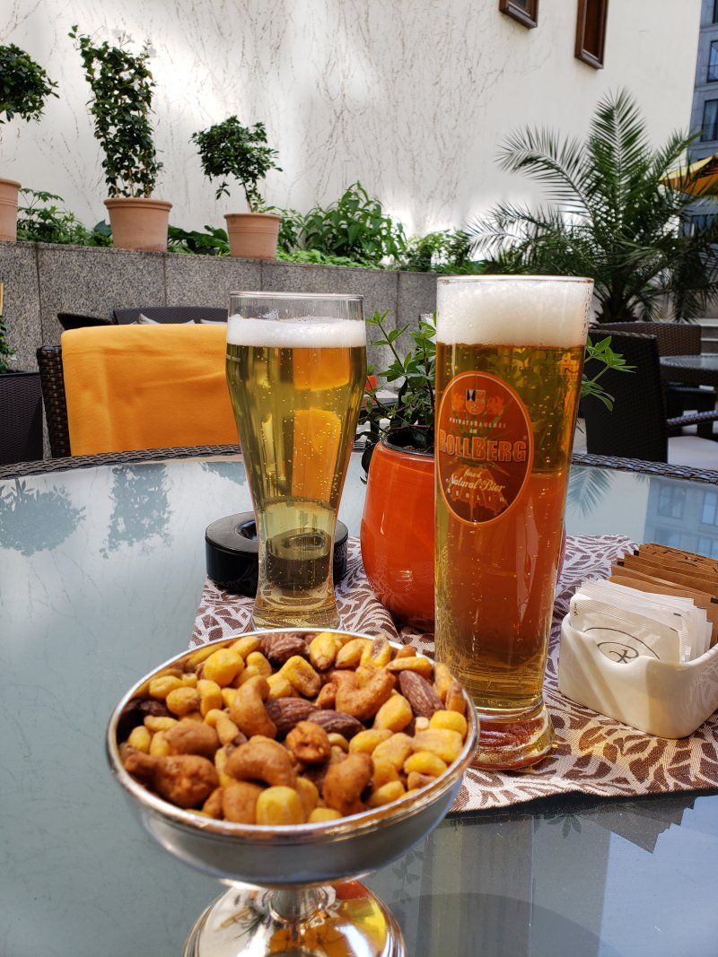 Two glasses of beer and a bowl of nuts on a table