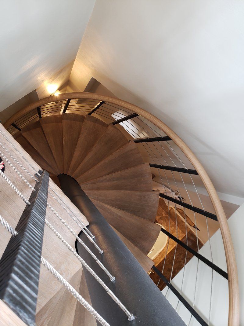 A spiral staircase with a wooden railing and ropes