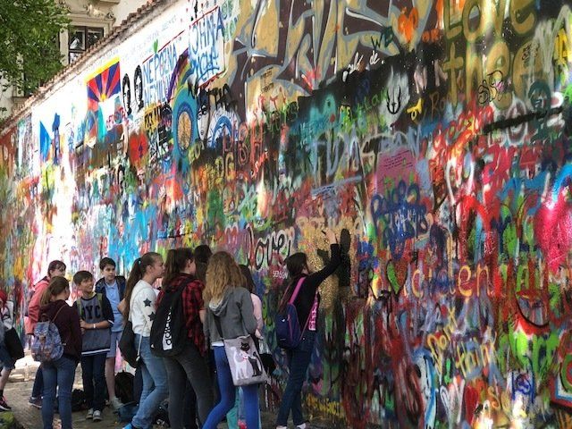 A group of people are standing in front of a wall covered in graffiti.