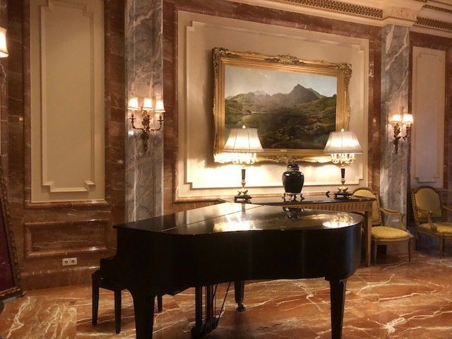 A piano in a room with a painting on the wall above it