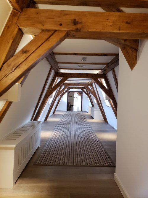 A long hallway with wooden beams and a rug
