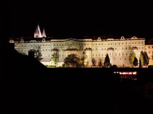 A large building is lit up at night with a church in the background.