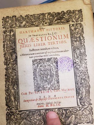 A person is holding a book titled questionum juris liber tertius