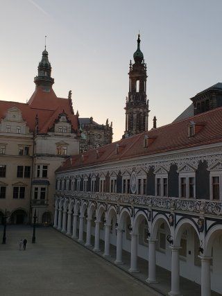 A large building with arches and a clock tower in the background
