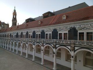 A large building with arches and a clock tower in the background