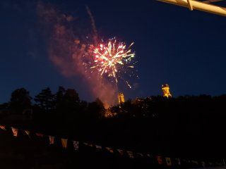 A fireworks display is taking place in the night sky over a city.