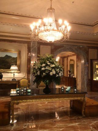 A table with a vase of flowers on it in a room with a chandelier