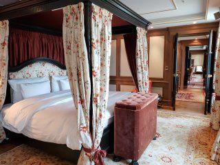 A bedroom with a four poster bed and a stool