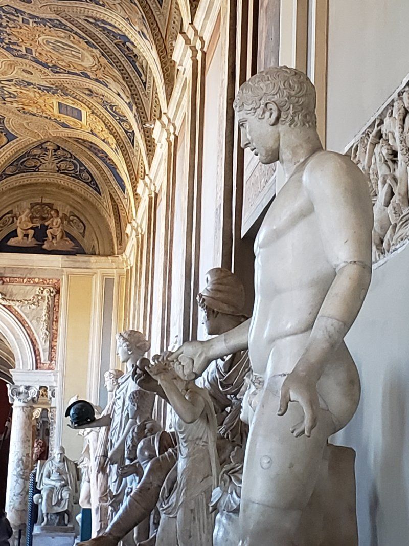 A statue of a man standing next to another statue in a museum.