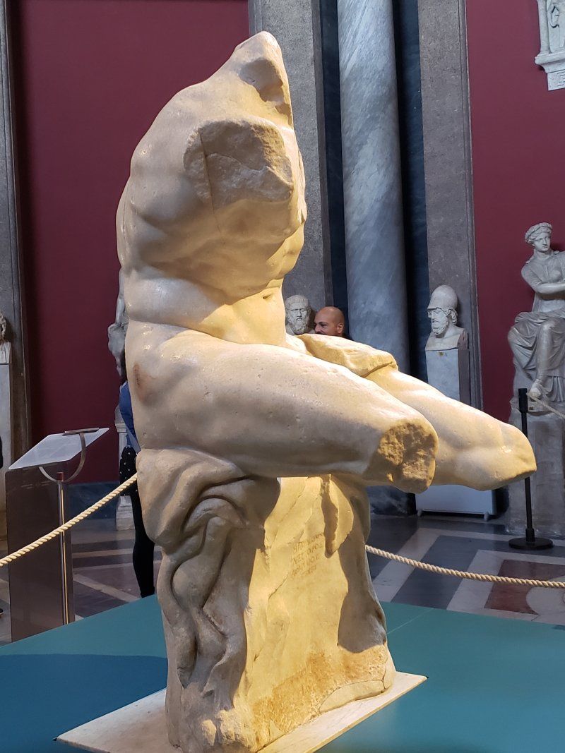 A statue of a man is sitting on a table in a museum.