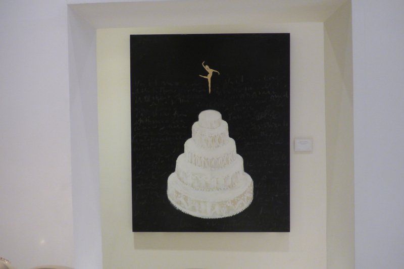 A painting of a cake with a ballerina on top of it