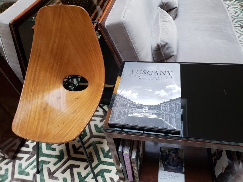 A book titled tuscany sits on a table next to a chair