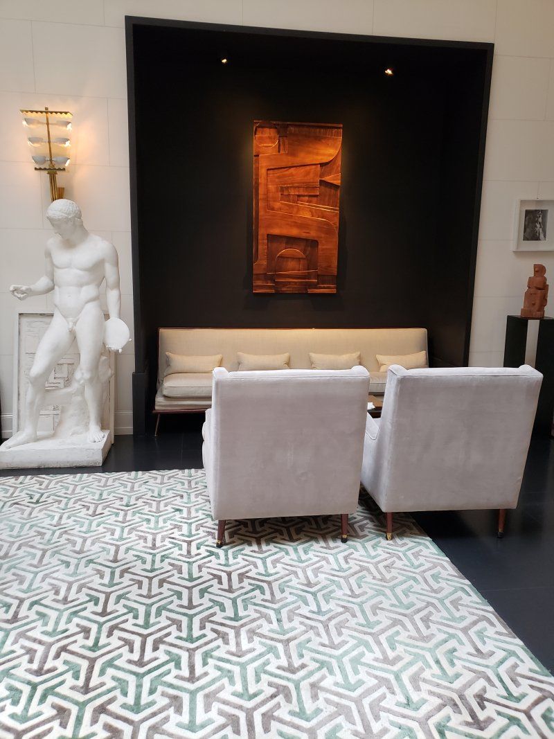 A living room with two chairs and a statue on the wall
