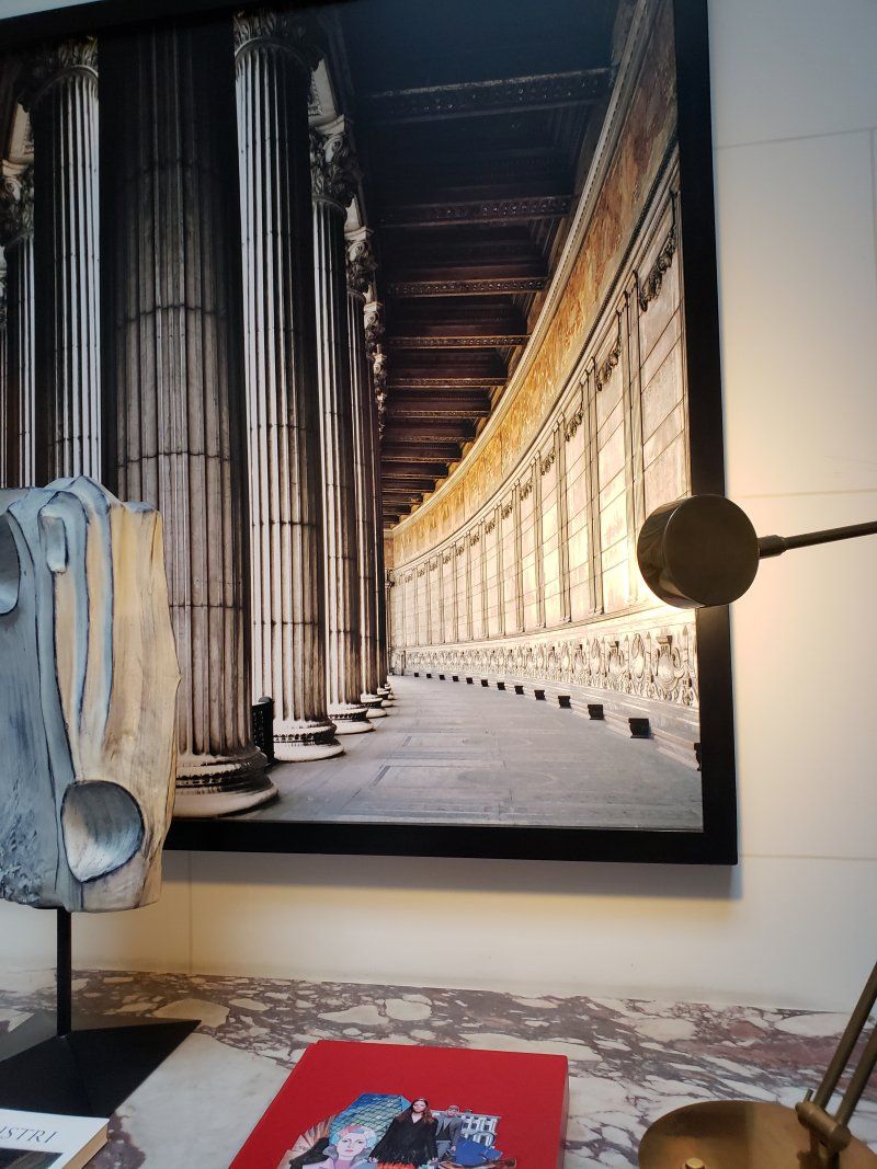 A picture of a building with columns is hanging on a wall.