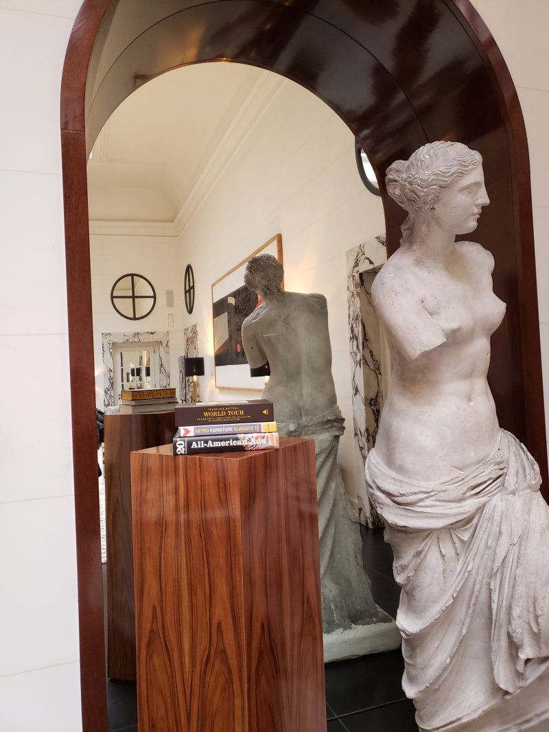 A statue of a woman sitting on a wooden pedestal in a room